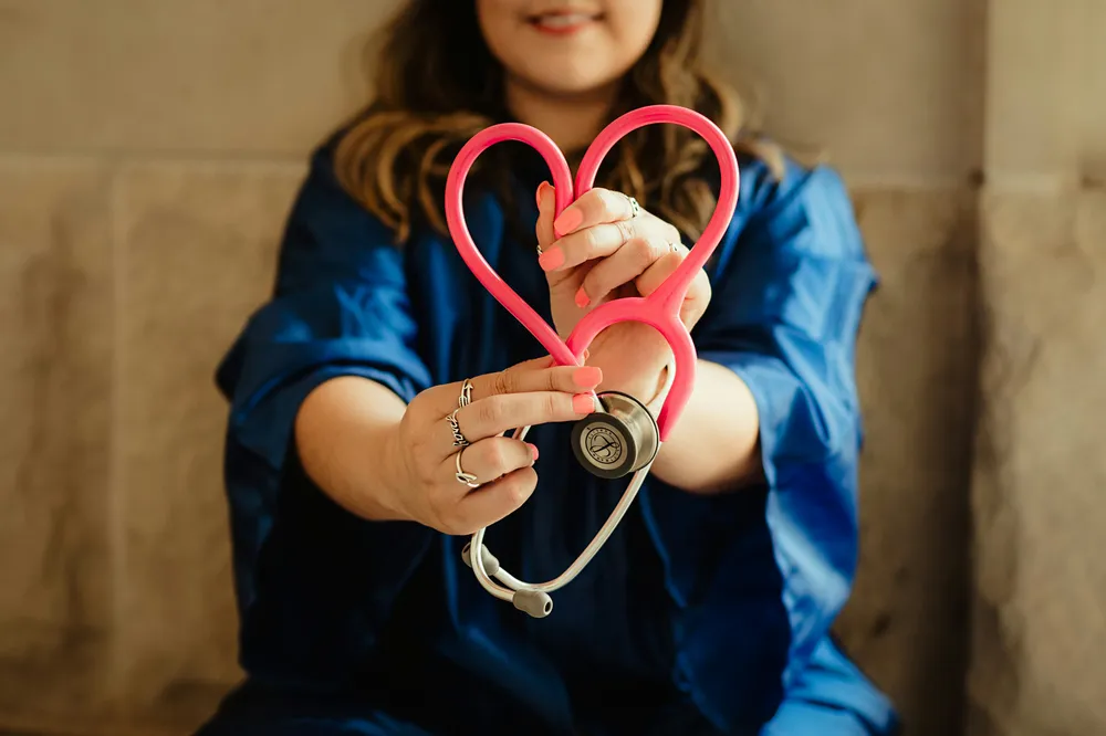 Profesional de enfermería sosteniendo un estetoscopio en forma de corazón
